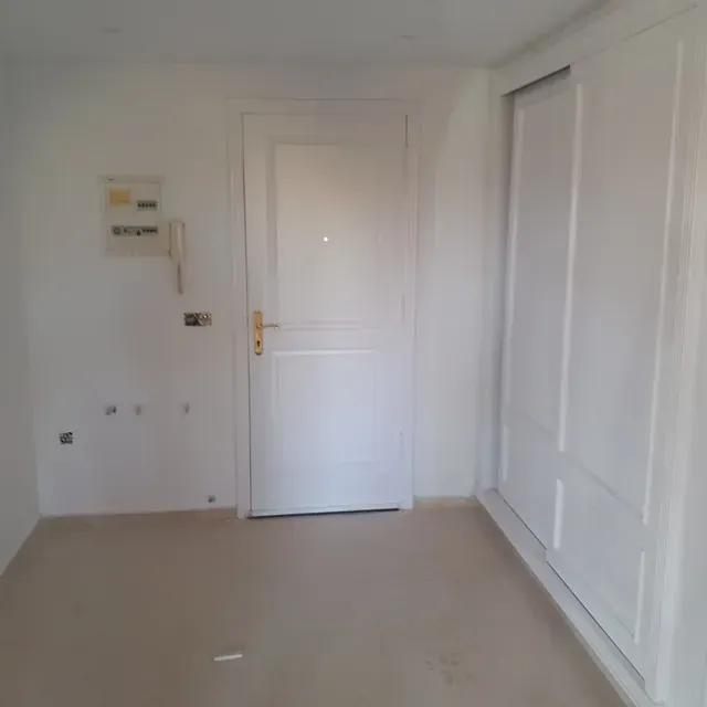 Una habitación vacía con una puerta y un teléfono en la pared.