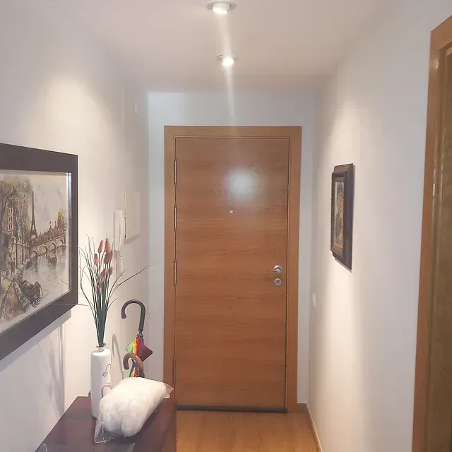 Un pasillo con una puerta de madera y un cuadro en la pared.