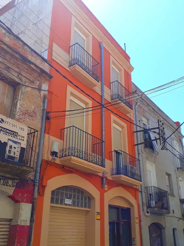 Un edificio naranja con balcones y un cartel que dice 'a' en él