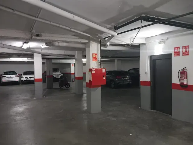 Un estacionamiento con autos y una motocicleta estacionados en él.