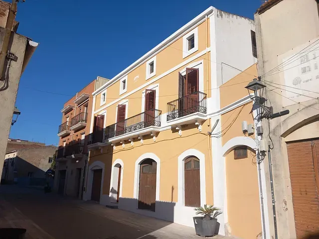 Un edificio amarillo y blanco con balcones y persianas.