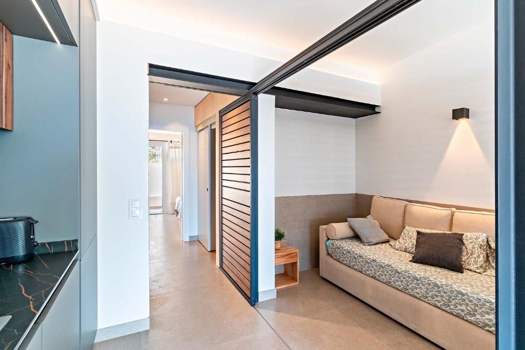 Interior de un apartamento moderno; se ven un sofá, puertas de listones de madera y una zona de cocina.