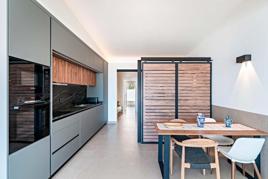Cocina moderna con armarios grises, detalles de madera y mesa de comedor.