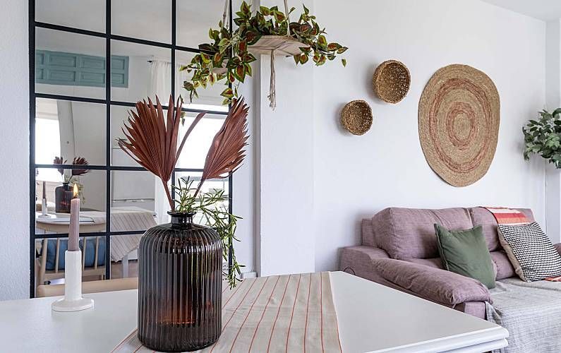 Interior con paredes blancas, pared con paneles de vidrio, plantas, cestas decorativas, 