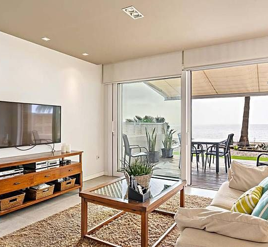 Sala de estar con vista a la playa a través de puertas corredizas