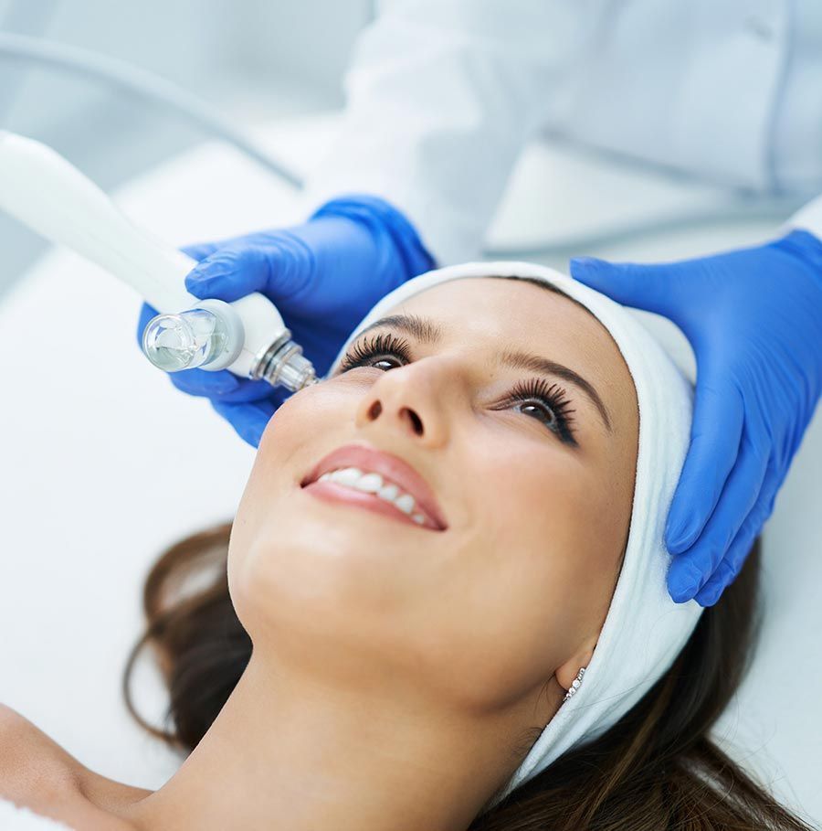 Una persona recibe un tratamiento facial profesional con un dispositivo manual para la piel mientras está tumbada en una camilla de spa.