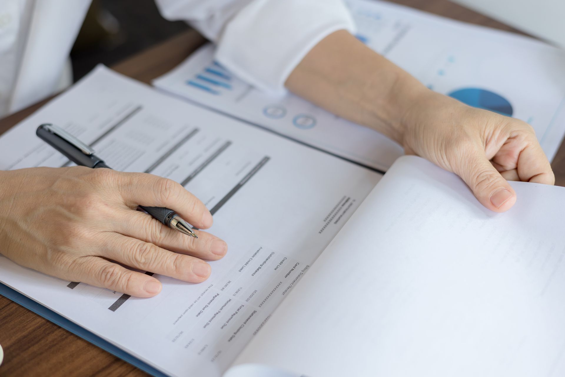 Eine Person schreibt mit einem Stift auf ein Blatt Papier.