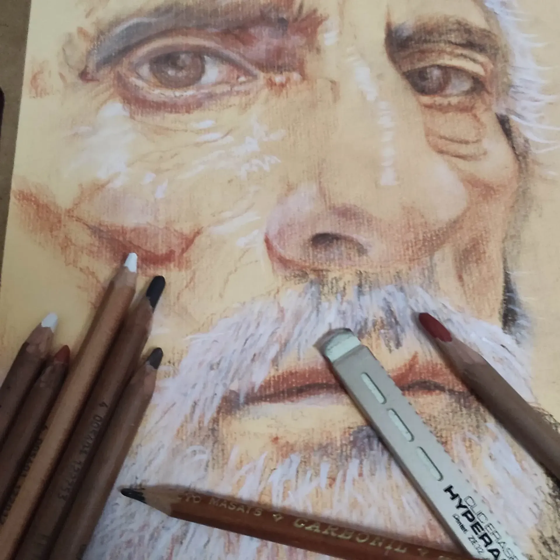 Un dibujo de un hombre con barba está rodeado de lápices de colores.