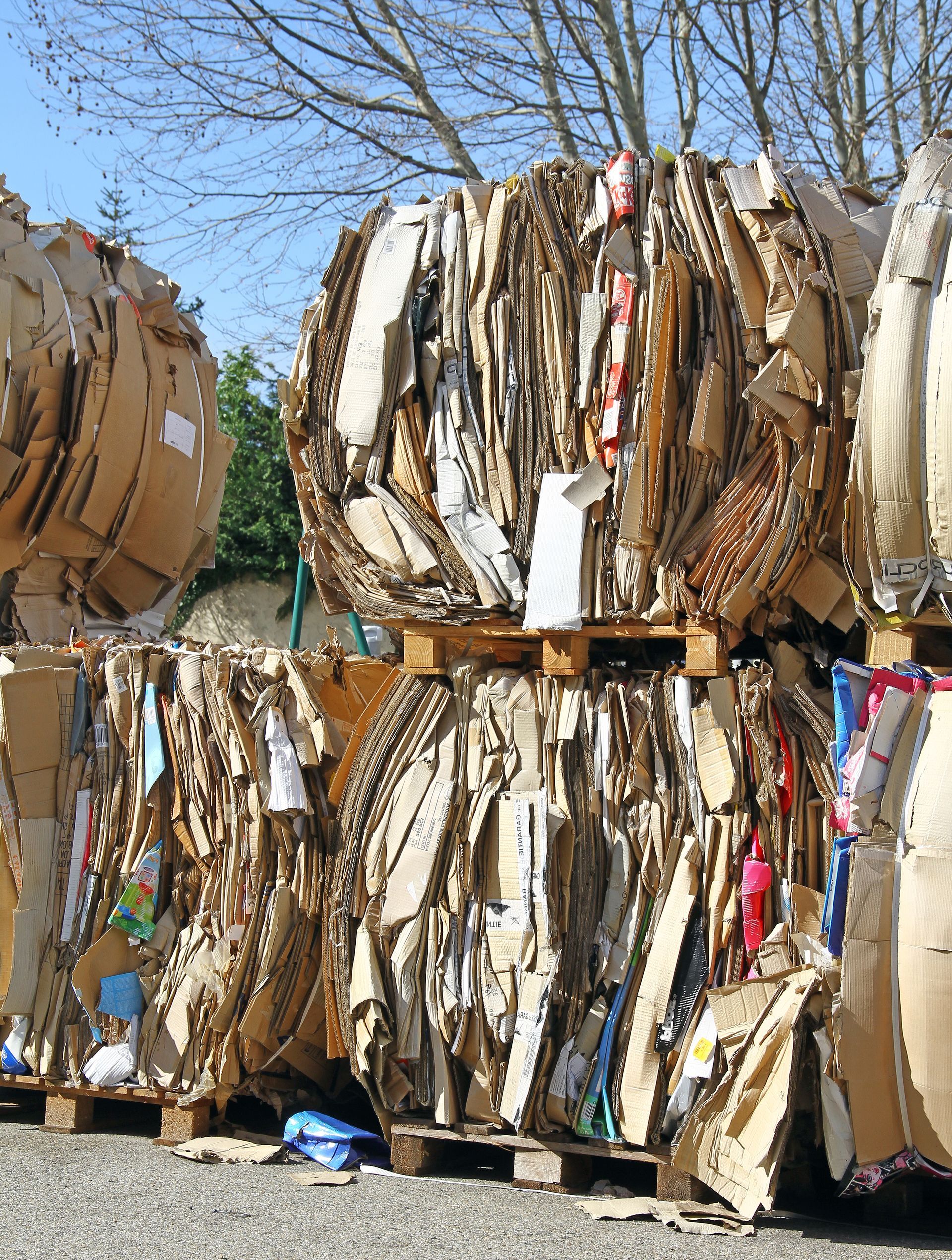 Ensemble de cartons aplatis sur palettes, à l'extérieur.