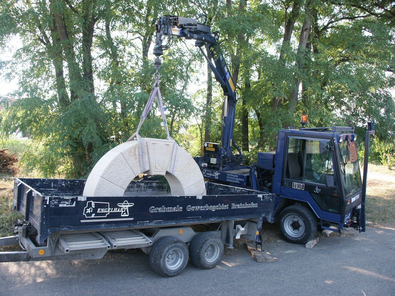 Ein Kran hebt einen großen Stein auf die Ladefläche eines Lastwagens