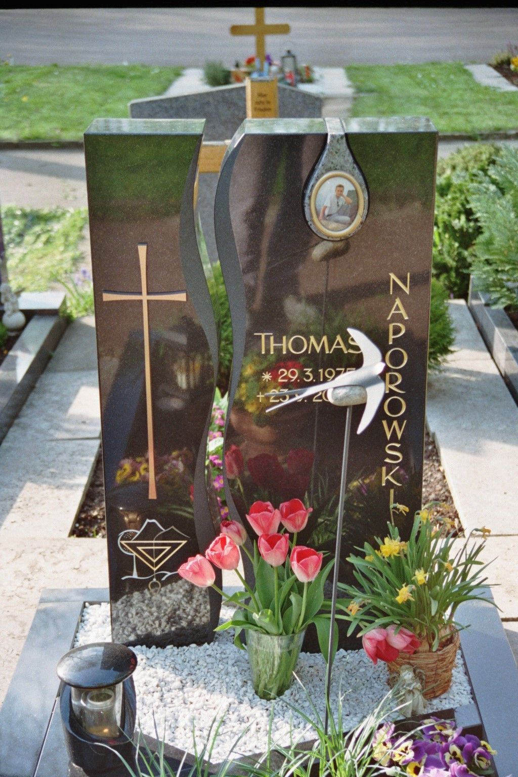 Ein Grab mit Blumen und einem Kreuz mit der Aufschrift Thomas