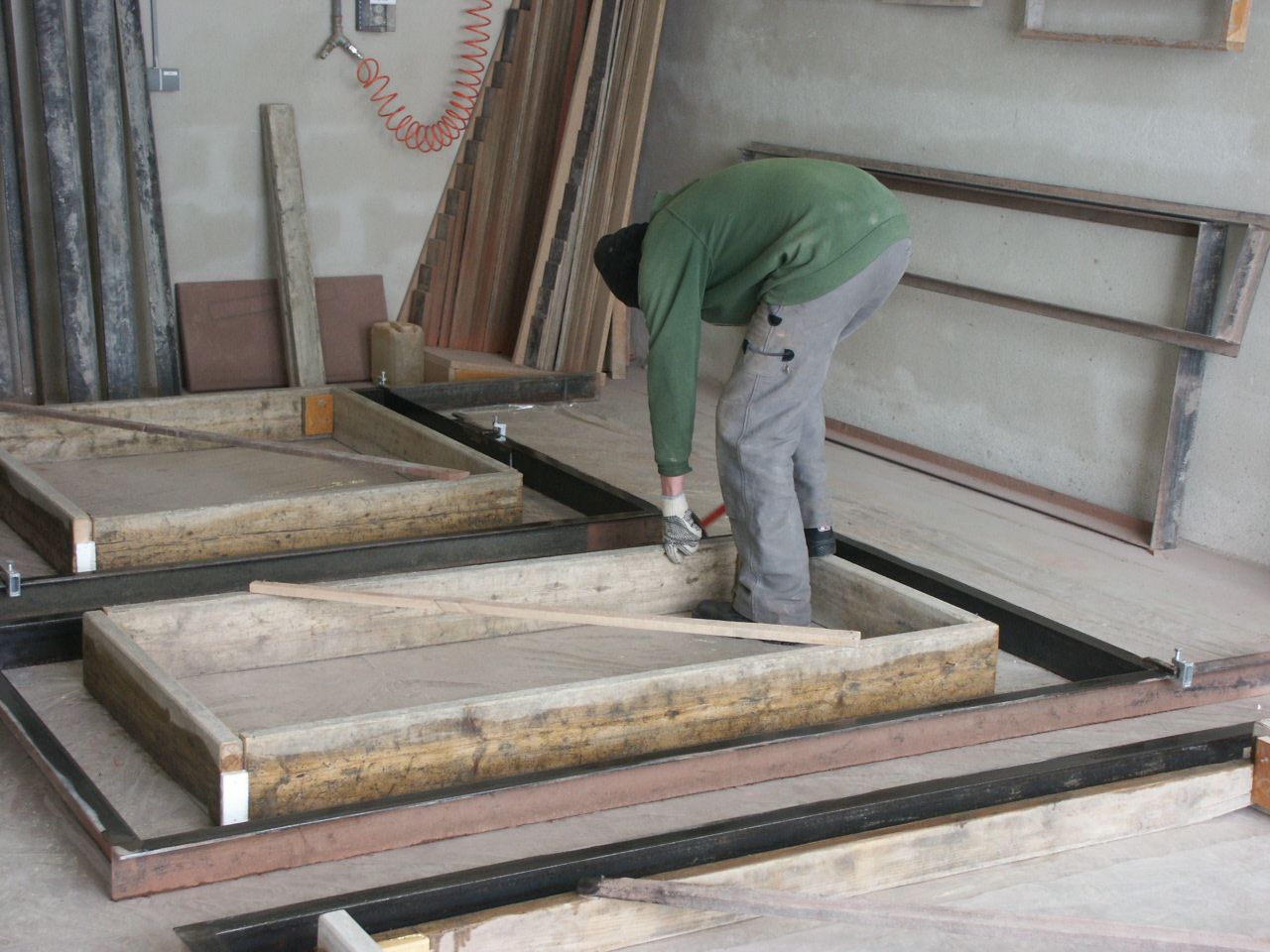 Ein Mann im grünen Hemd arbeitet an einem Stück Holz
