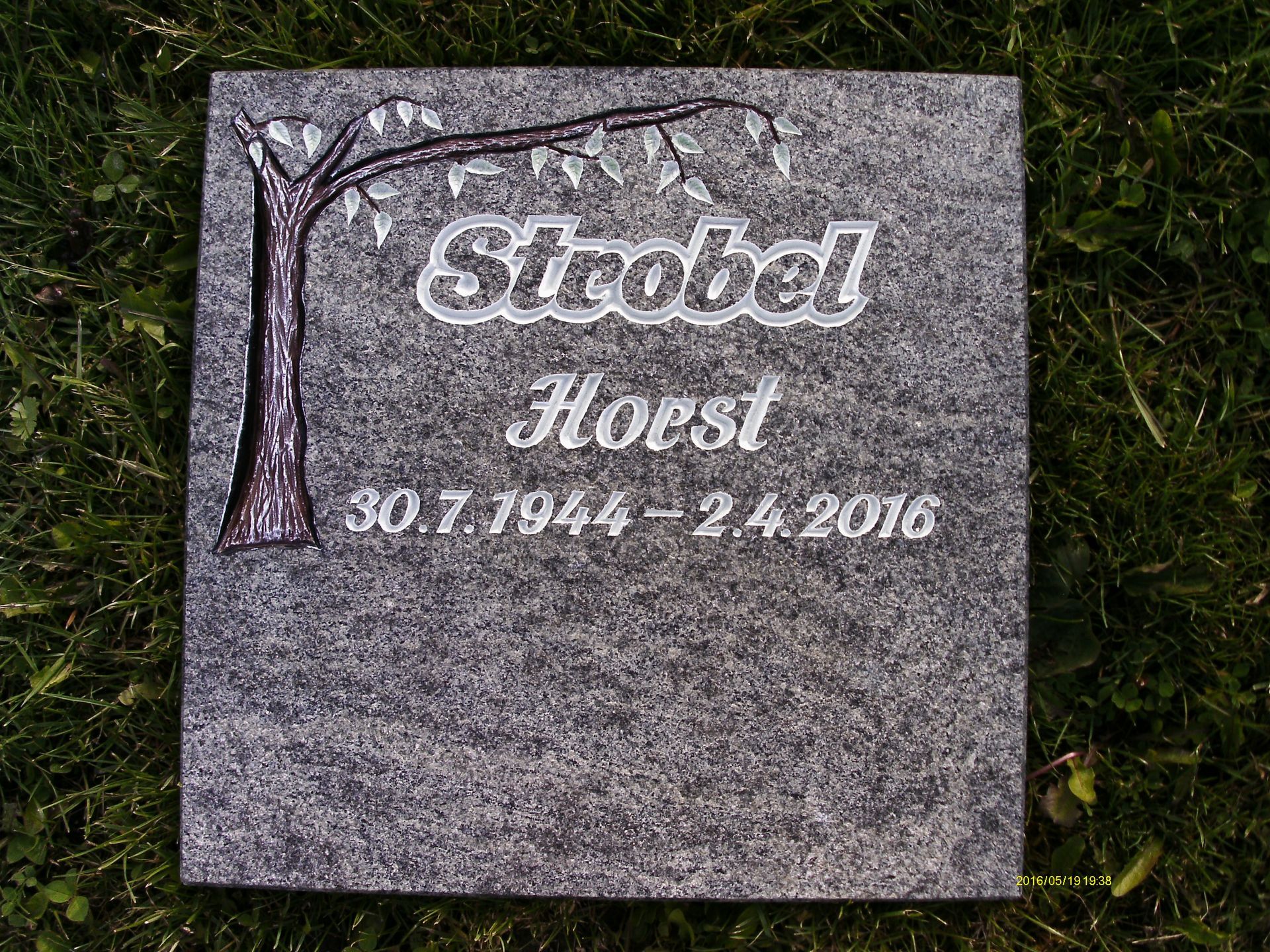 Ein Grabstein für Horst Strobel liegt im Gras.