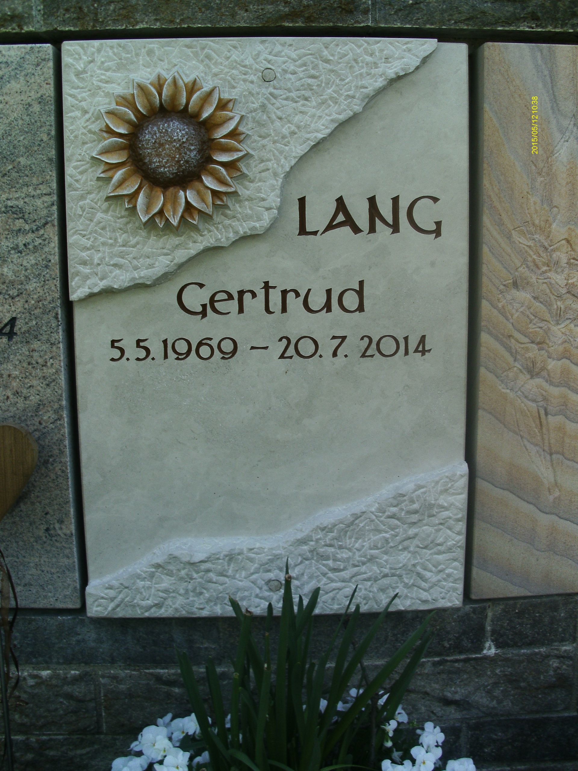 Ein Grabstein für Gertrud Lang mit einer Sonnenblume darauf