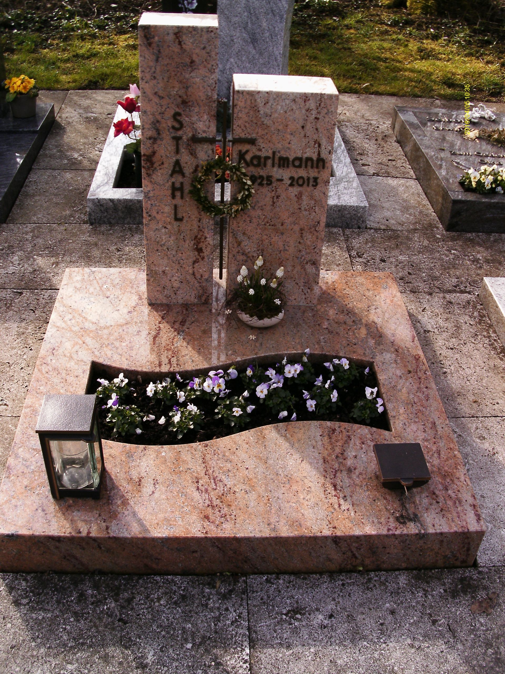 Ein Grab auf einem Friedhof mit Blumen und einer Laterne