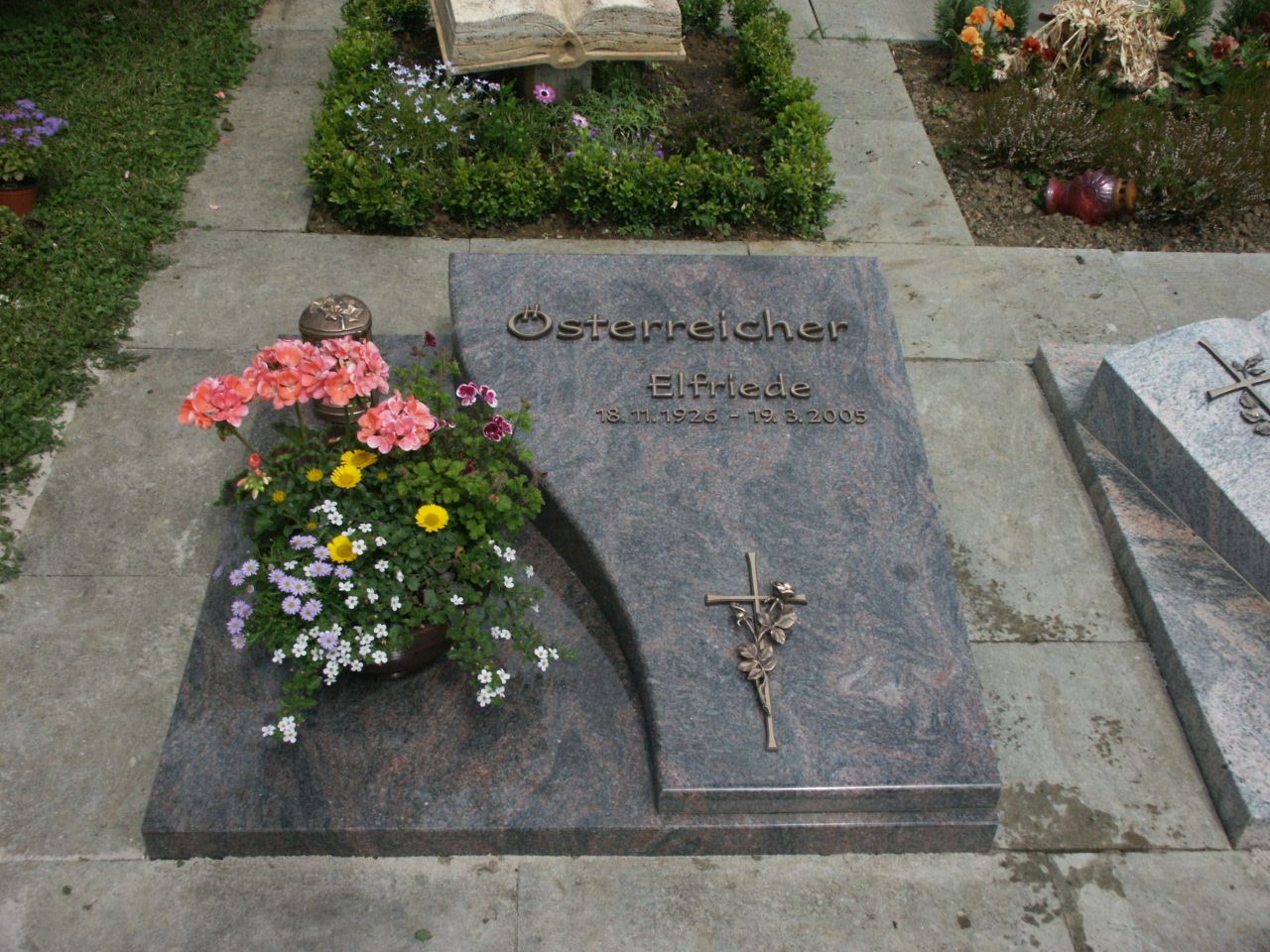 Ein Grab mit Blumen und einem Kreuz darauf