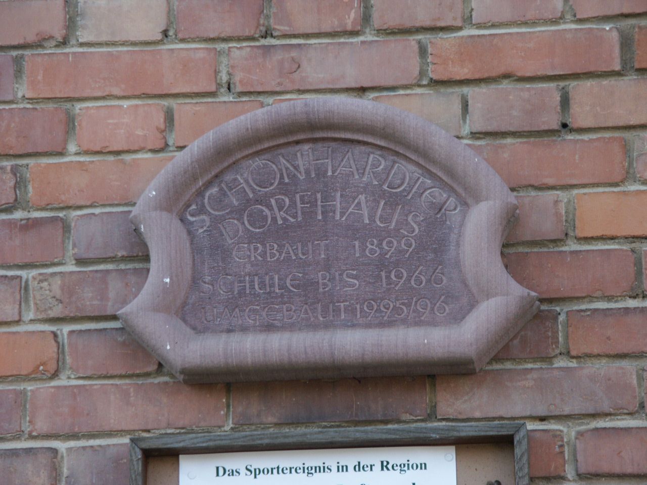 Profilierte Schrifttafel aus Sandstein mit zurückgesetzter Schriftfläche und eingehauener Schrift.