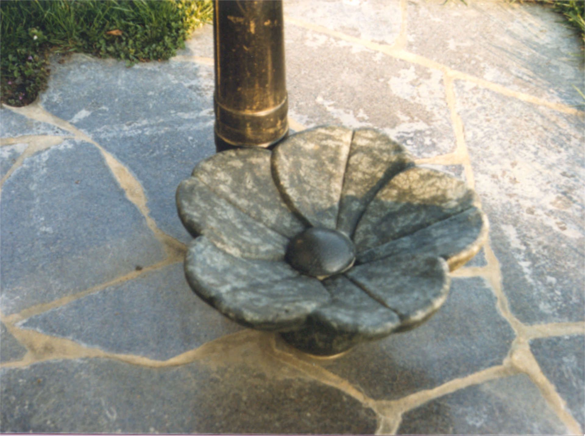 Ausgussbecken an einer Gartenpumpe in Blütenform aus Diabas (Hartbasalt).