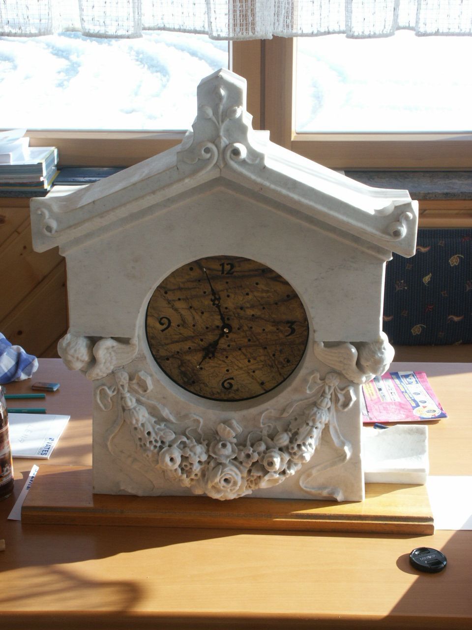 Eine weiße Uhr auf einem Holztisch mit einem Fenster im Hintergrund