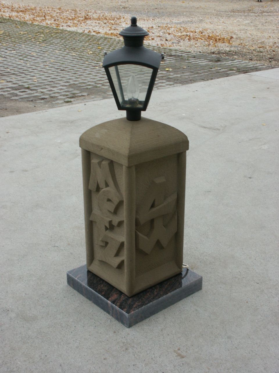 Lampenunterbau mit Ornamentik und Schrift aus Sandstein.