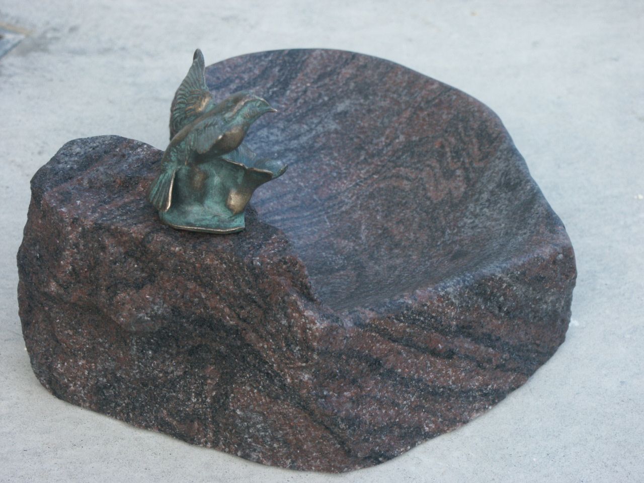 Vogeltränke aus Granit in Herzform mit Bronzevogel.