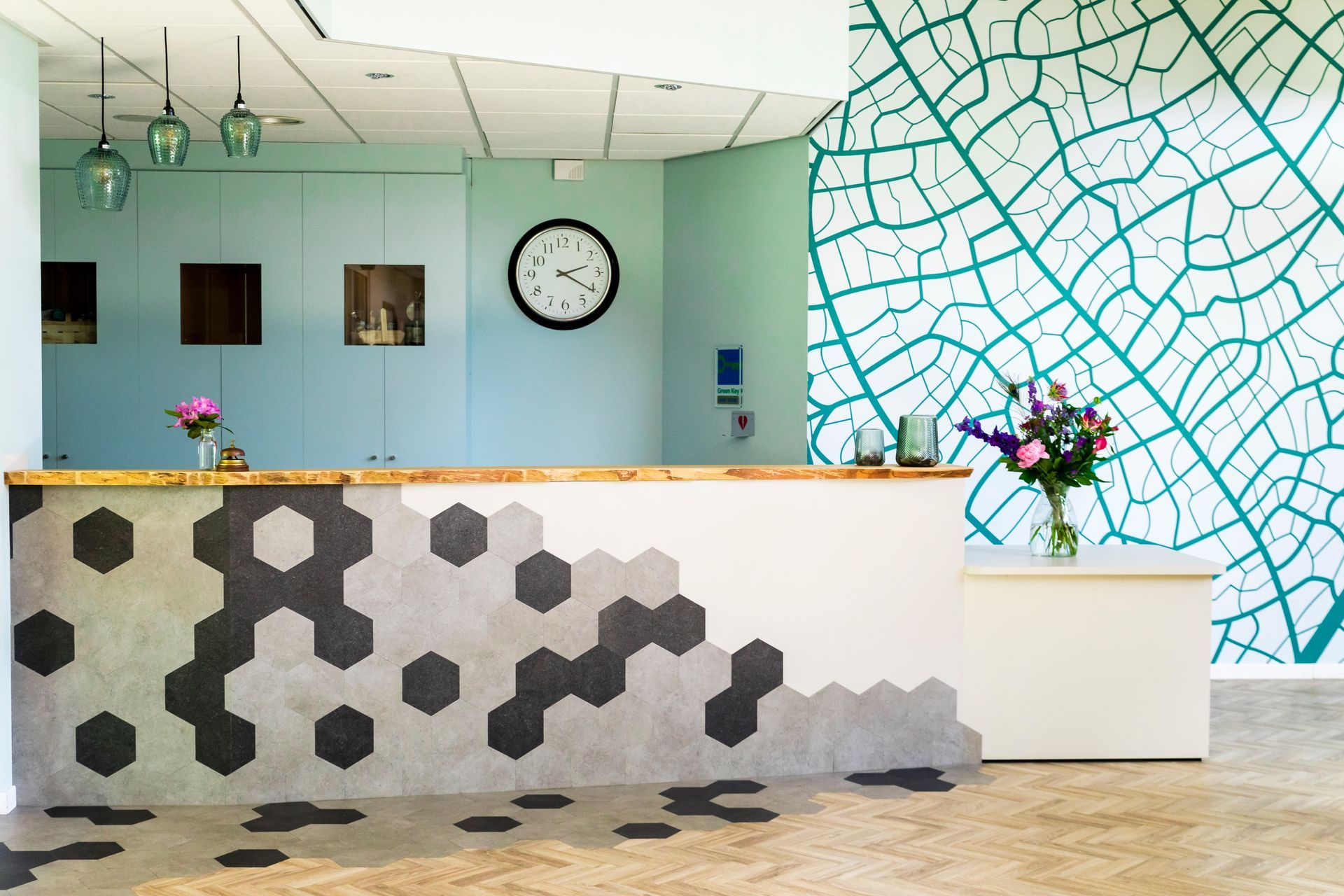 Receptiebalie met geometrisch tegelontwerp en wand met bladmotief.