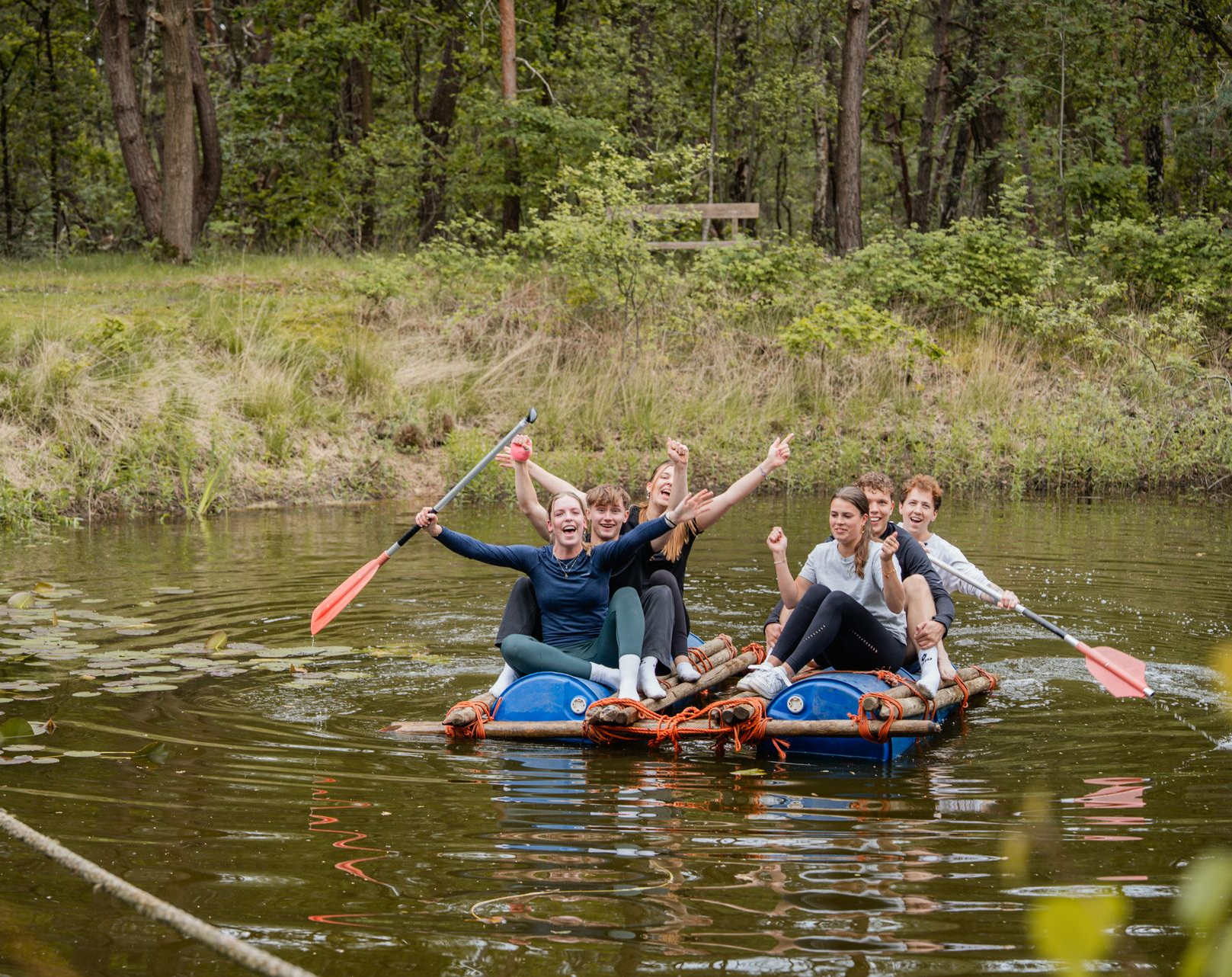 Kinderen en de leerkracht schilderen buiten in een zonnig park aan schildersezels.