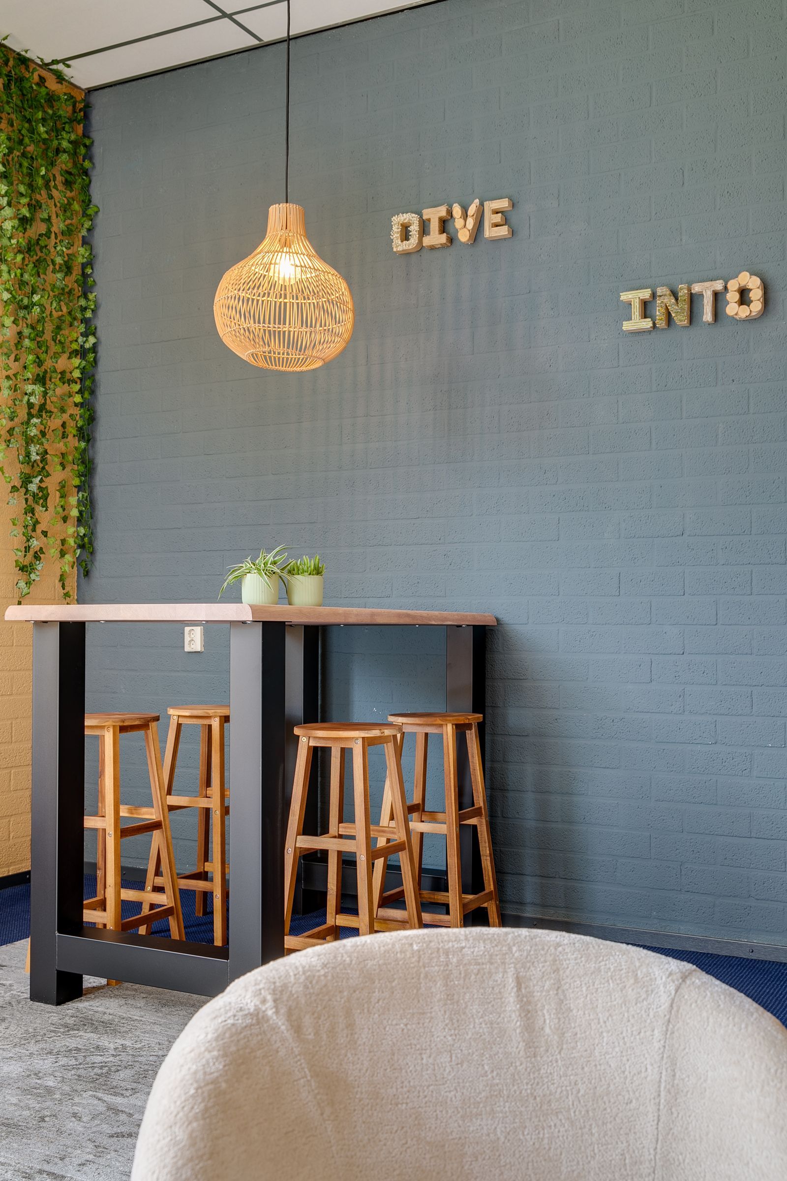 Houten bartafel met krukken voor een blauwe bakstenen muur. De letters 