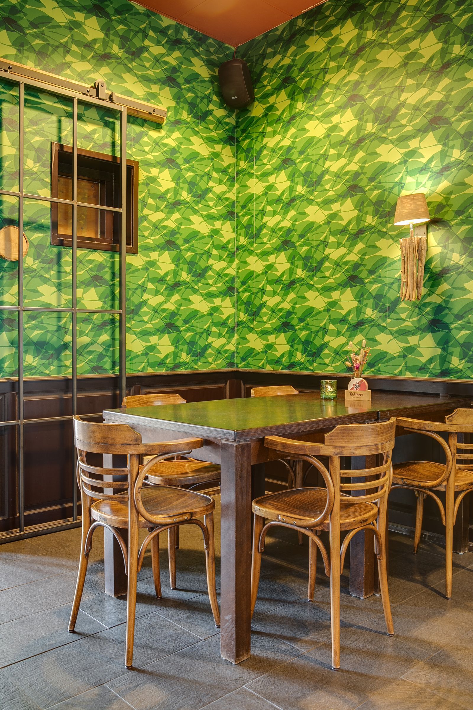 Eettafel en stoelen in een kamer met behang met een groen boommotief.