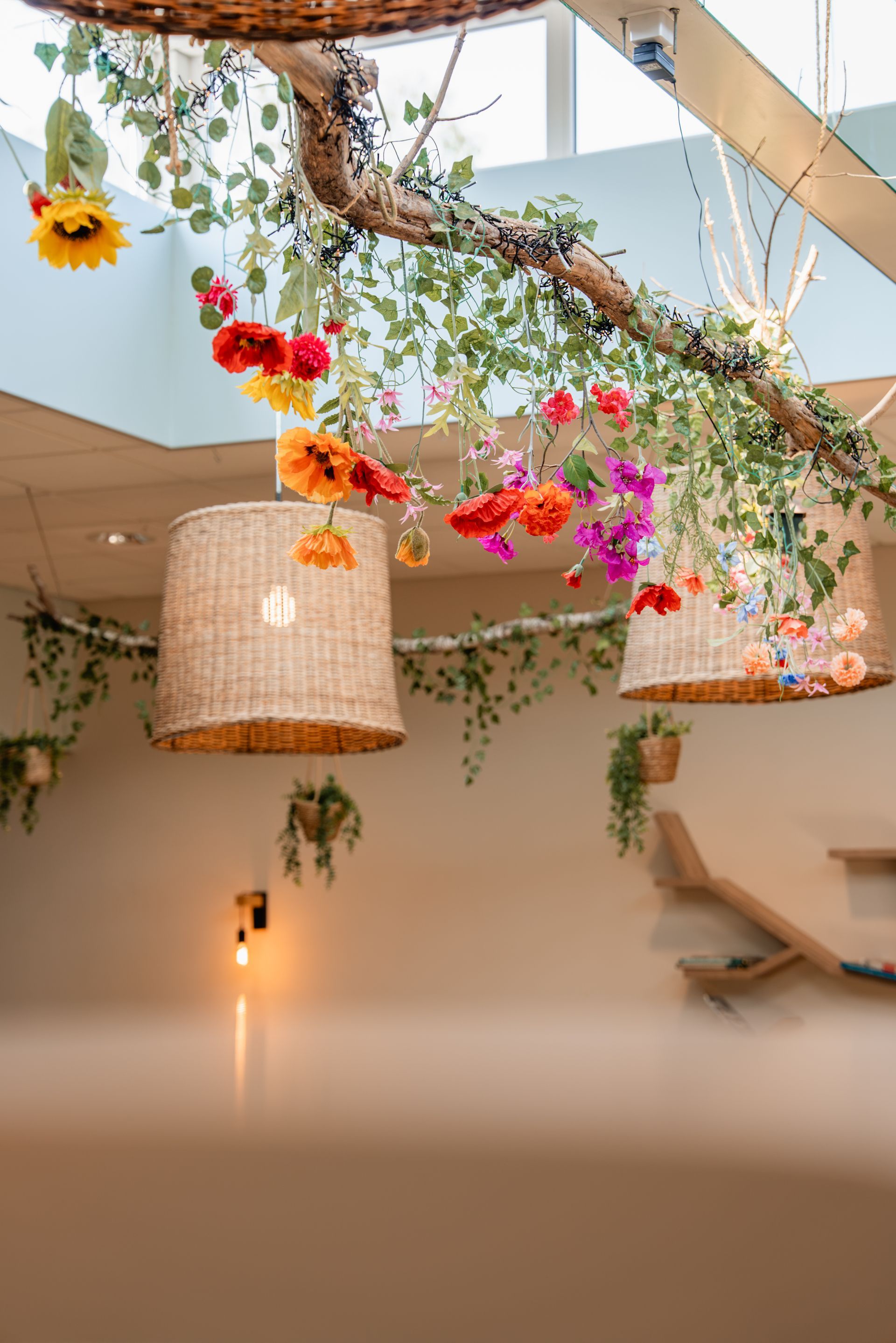 Gezellige lounge met twee hangstoelen, een zachte bank en een bloemstuk bij het raam.
