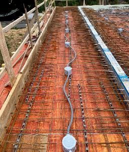 Baustelle: Elektrische Leitungen und Verteilerdosen sind innerhalb eines Bewehrungsgitters verlegt und bereit für den Betoniervorgang.