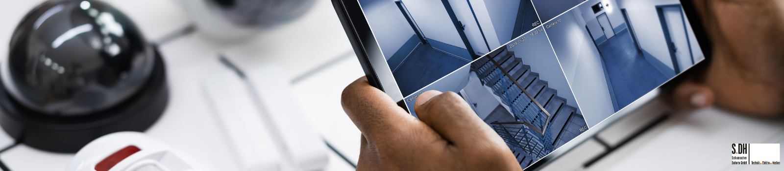 Eine Person hält ein Tablet mit einer Übersicht über Überwachungskamera eingebaut von SDH in Overath