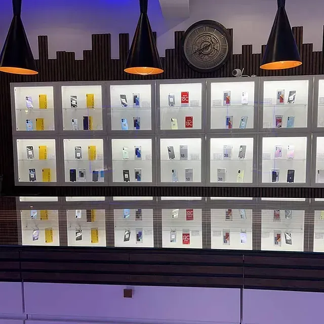 Una exhibición de teléfonos celulares en una tienda con un reloj en la pared.