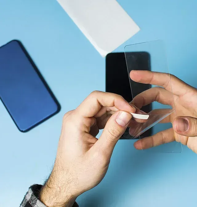 Una persona está colocando un protector de pantalla en un teléfono celular.