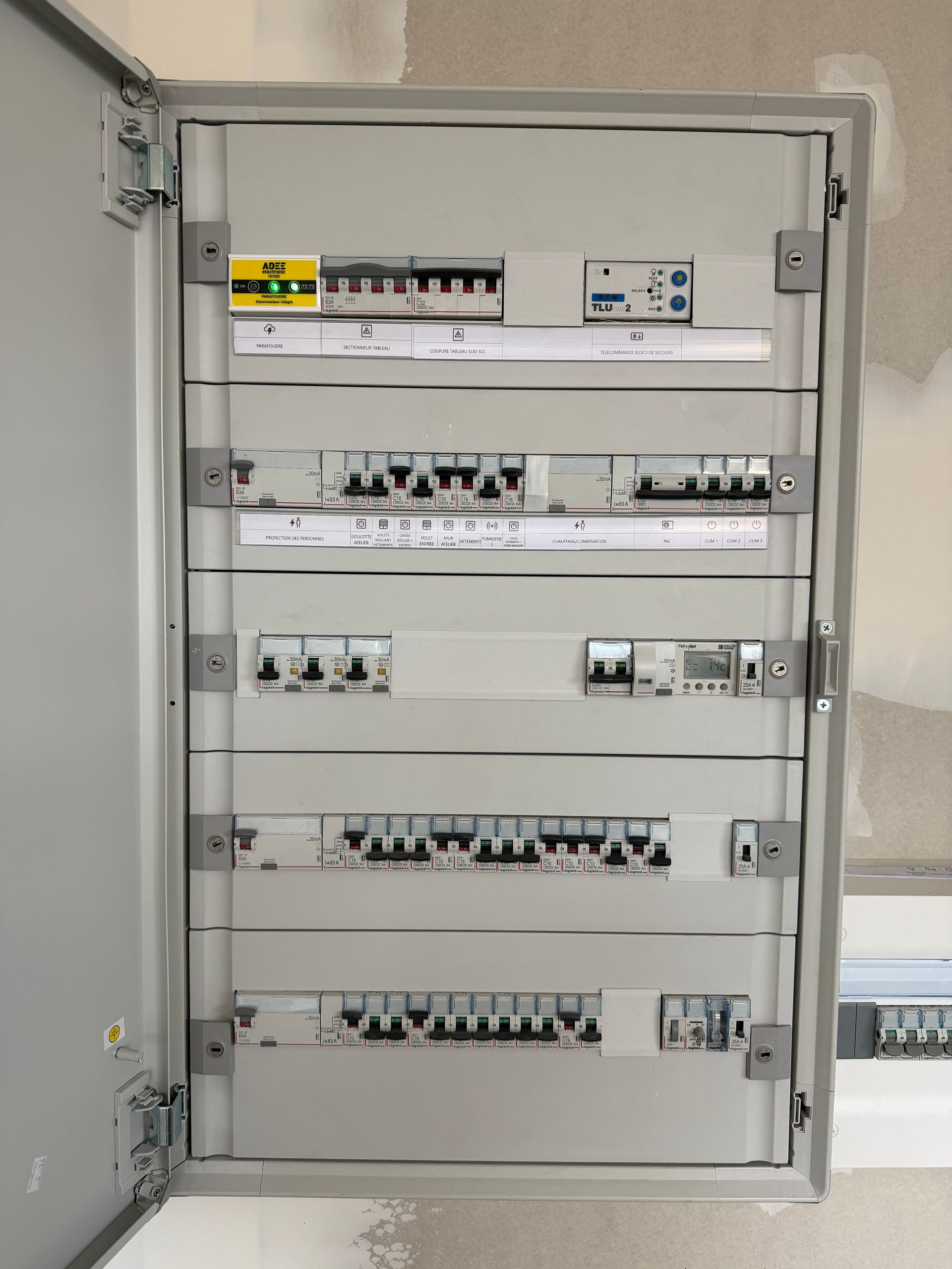 Deux armoires électriques industrielles ouvertes, fixées au mur, laissant apparaître les disjoncteurs internes et les composants de câblage.