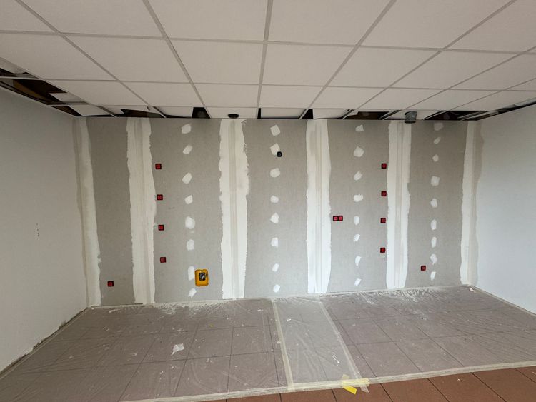 Pièce intérieure montrant un mur avec des joints de plaques de plâtre non finis et un faux plafond partiellement installé.