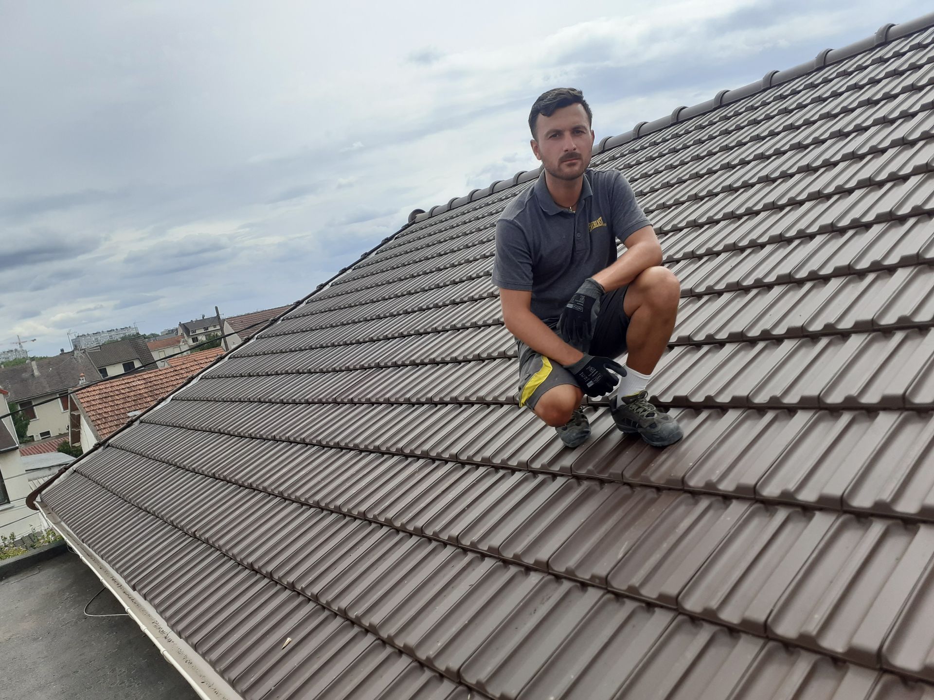 Deux ouvriers posent des bardeaux sur un toit en pente sous un soleil éclatant.