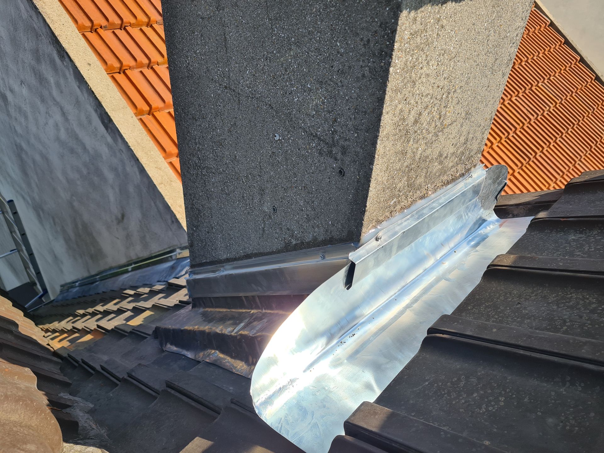 Un ouvrier pose des bardeaux d'asphalte bleu foncé sur un toit à l'aide d'un marteau.