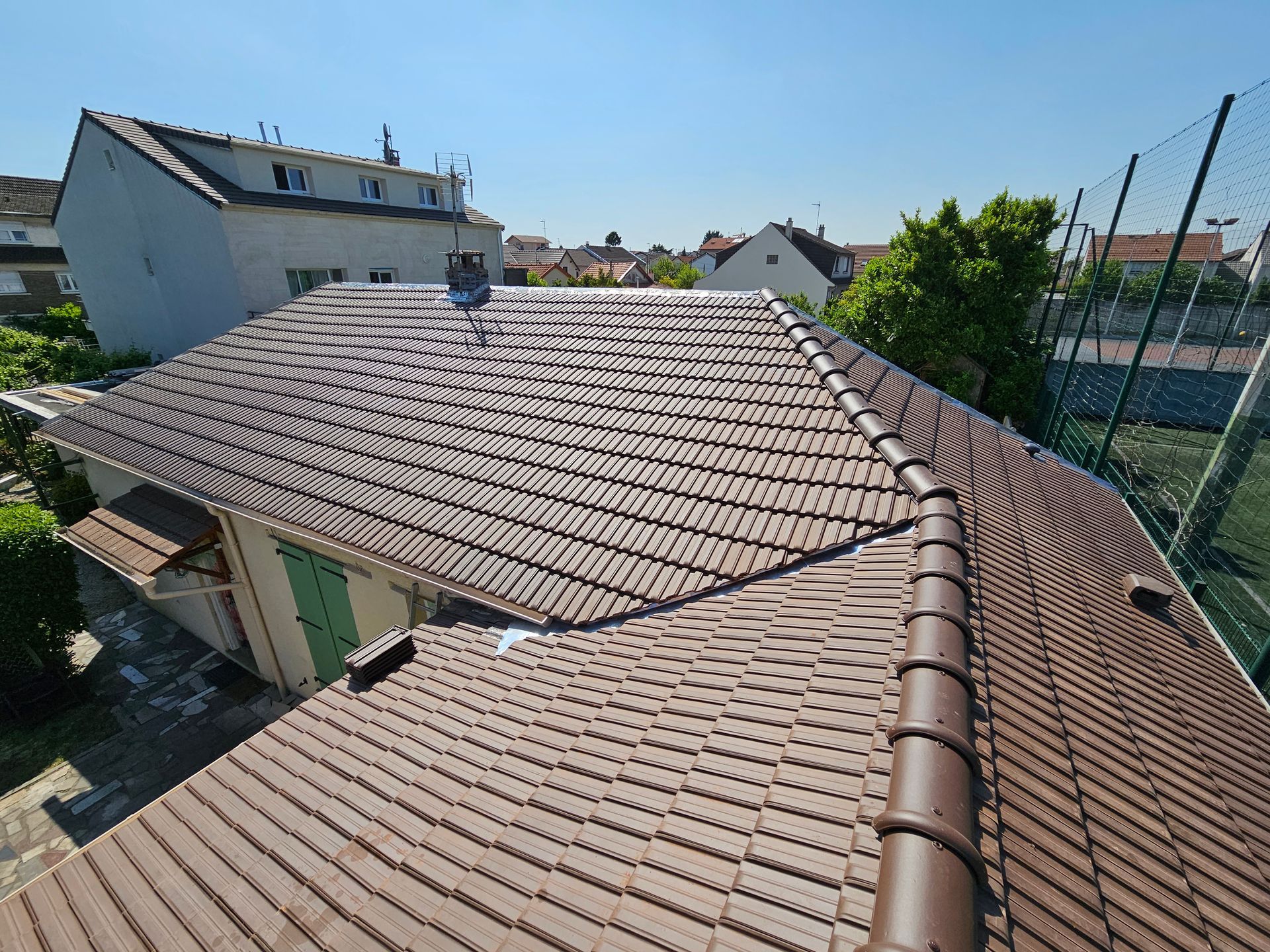 Des ouvriers du bâtiment installent des tuiles sur la charpente d'une maison au coucher du soleil.