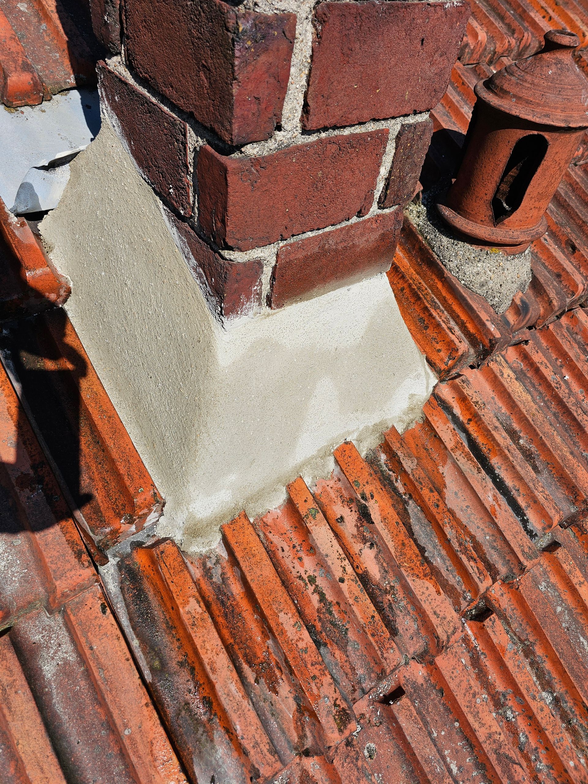 Des ouvriers réparent le toit en tuiles d'une maison, à l'aide d'échelles et d'échafaudages, sous un ciel bleu.