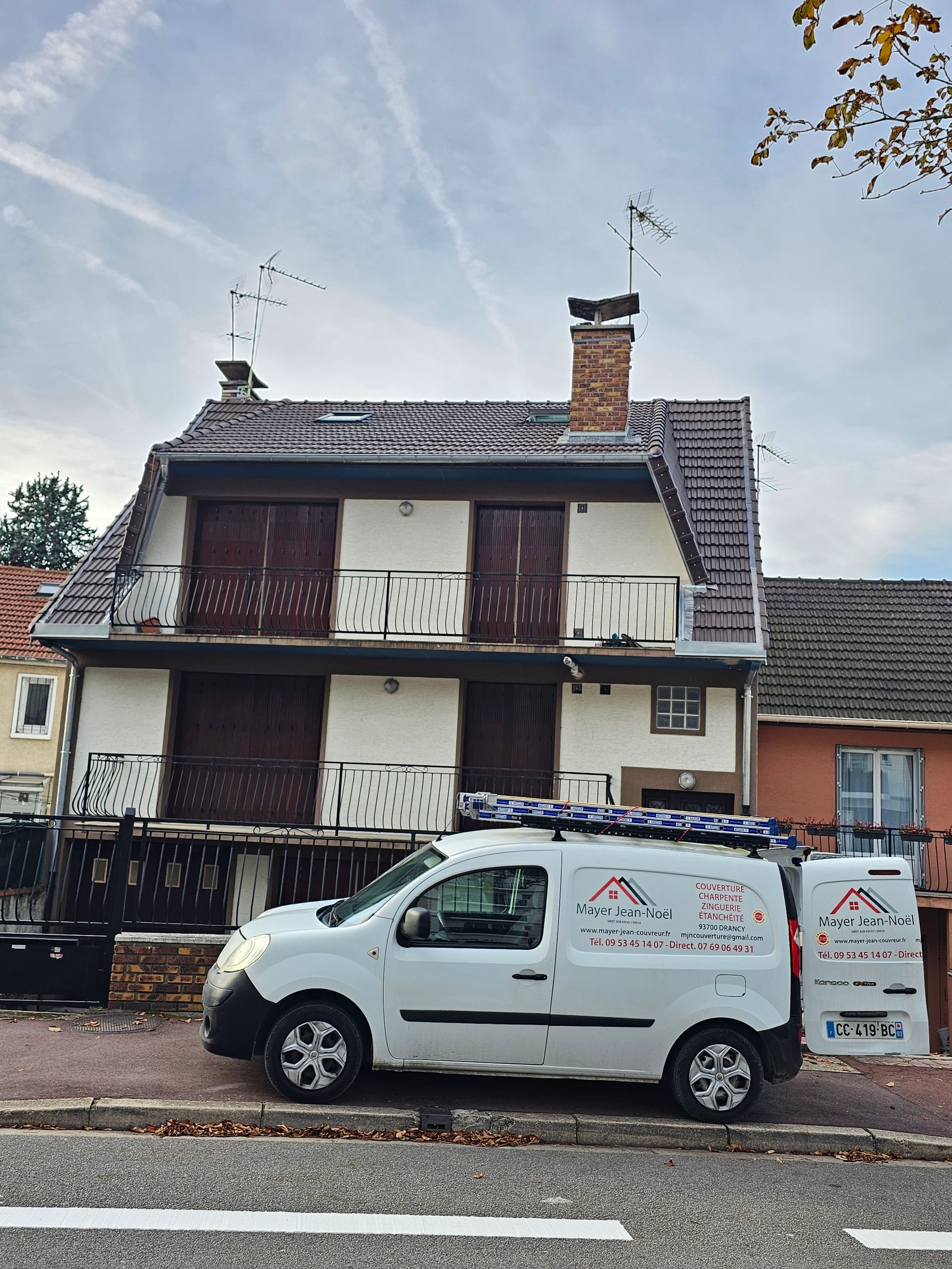 Des ouvriers réparent un toit en bardeaux à l'aide d'outils sur un toit pentu.