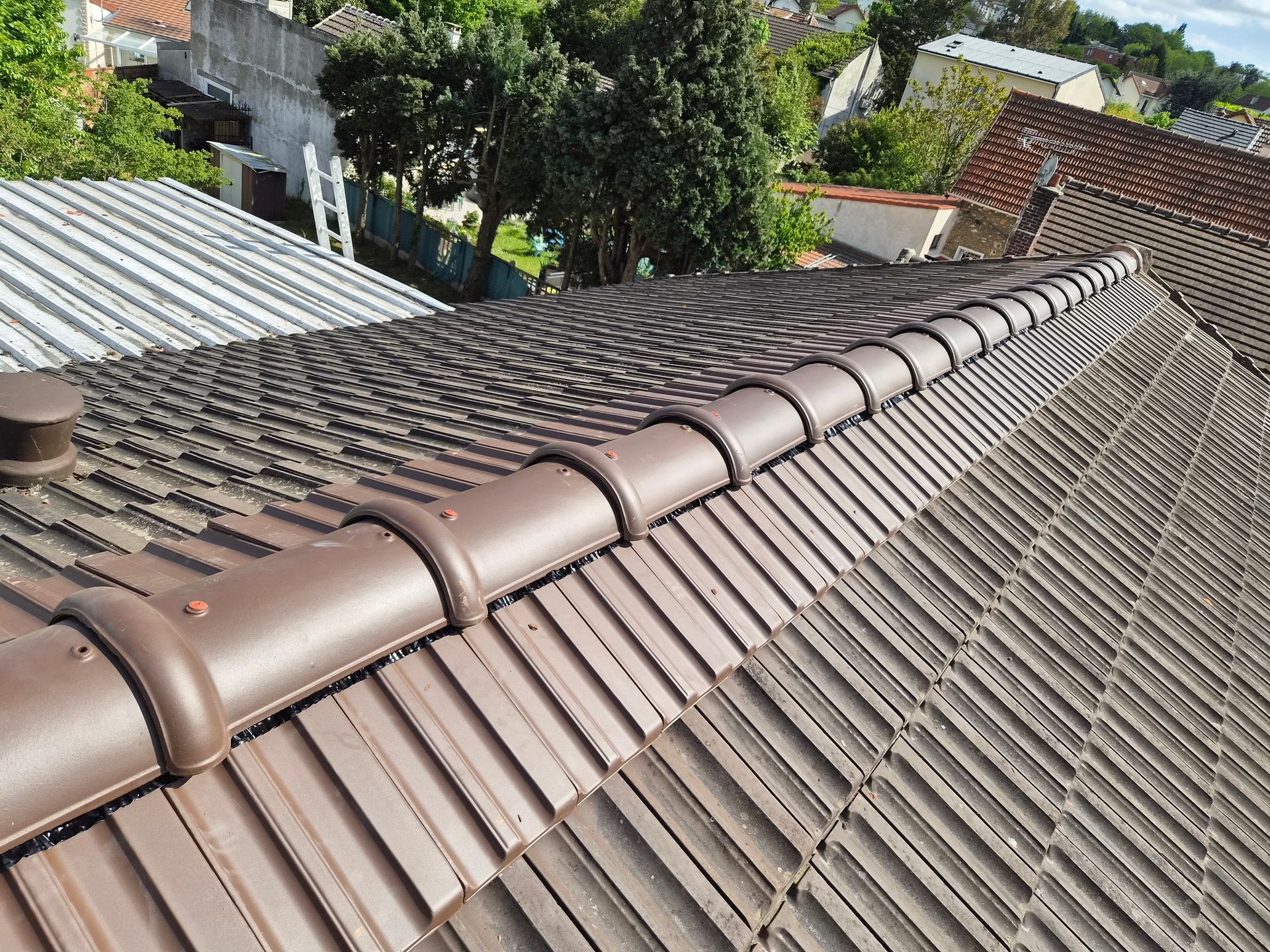 Ouvrier installant des tuiles bleues sur le toit d'une maison.