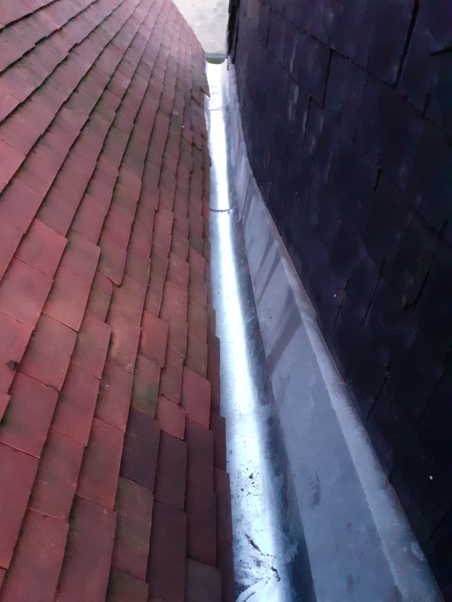 Eau de pluie ruisselant d'une gouttière et d'une descente pluviale.