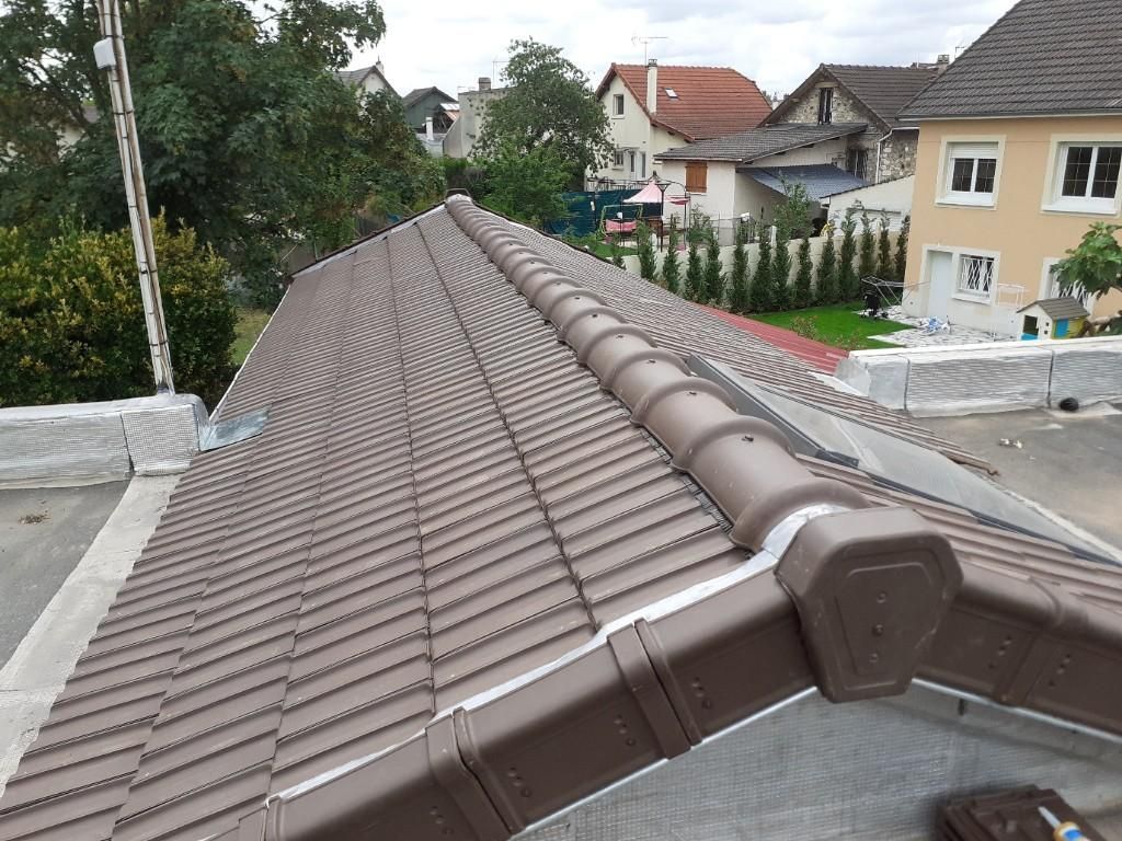 Toit de tuiles brunes sur une maison en construction, vue depuis la crête dans un quartier résidentiel.