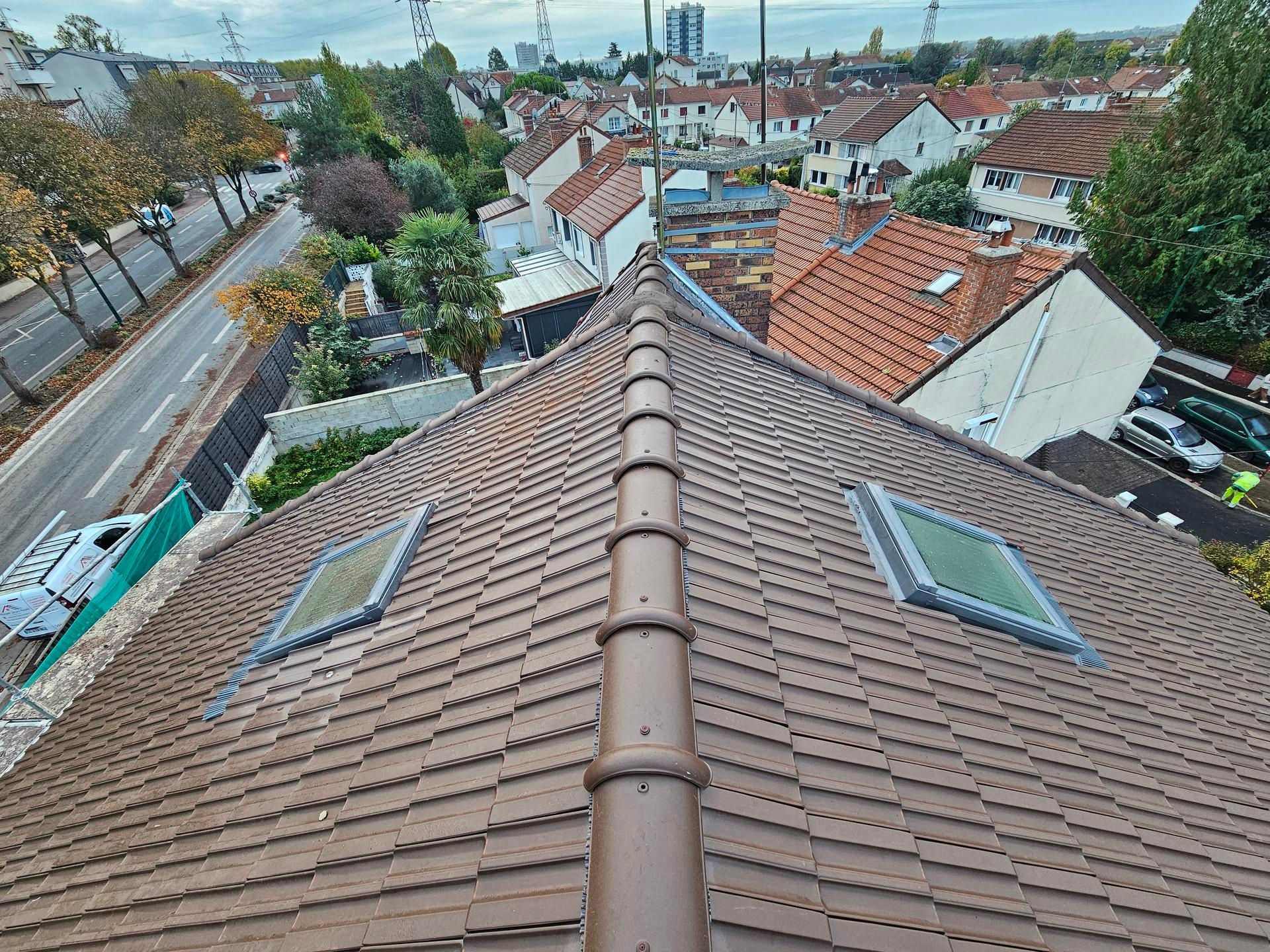Vue depuis un toit sur une rue de banlieue et les toits des maisons sous un ciel nuageux.