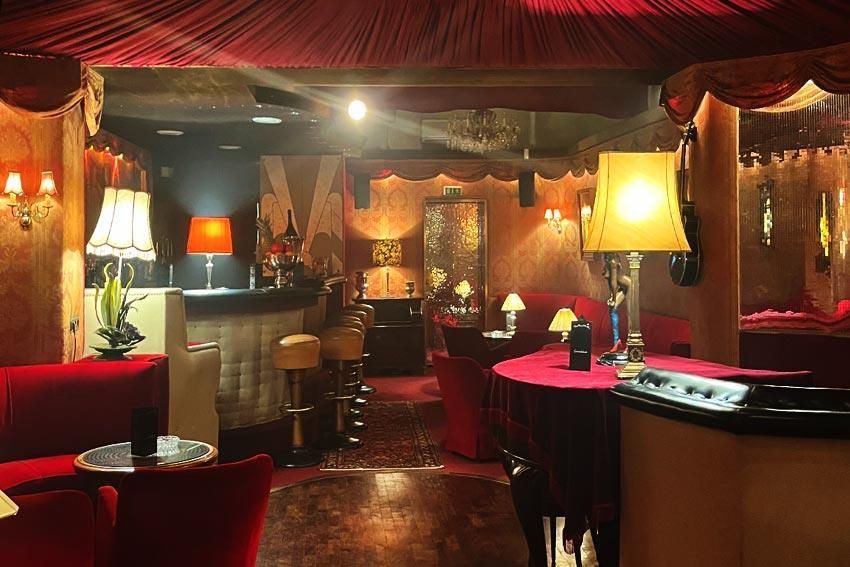 Ein Restaurant mit roten Stühlen, Tischen, Lampen und einer Bar.