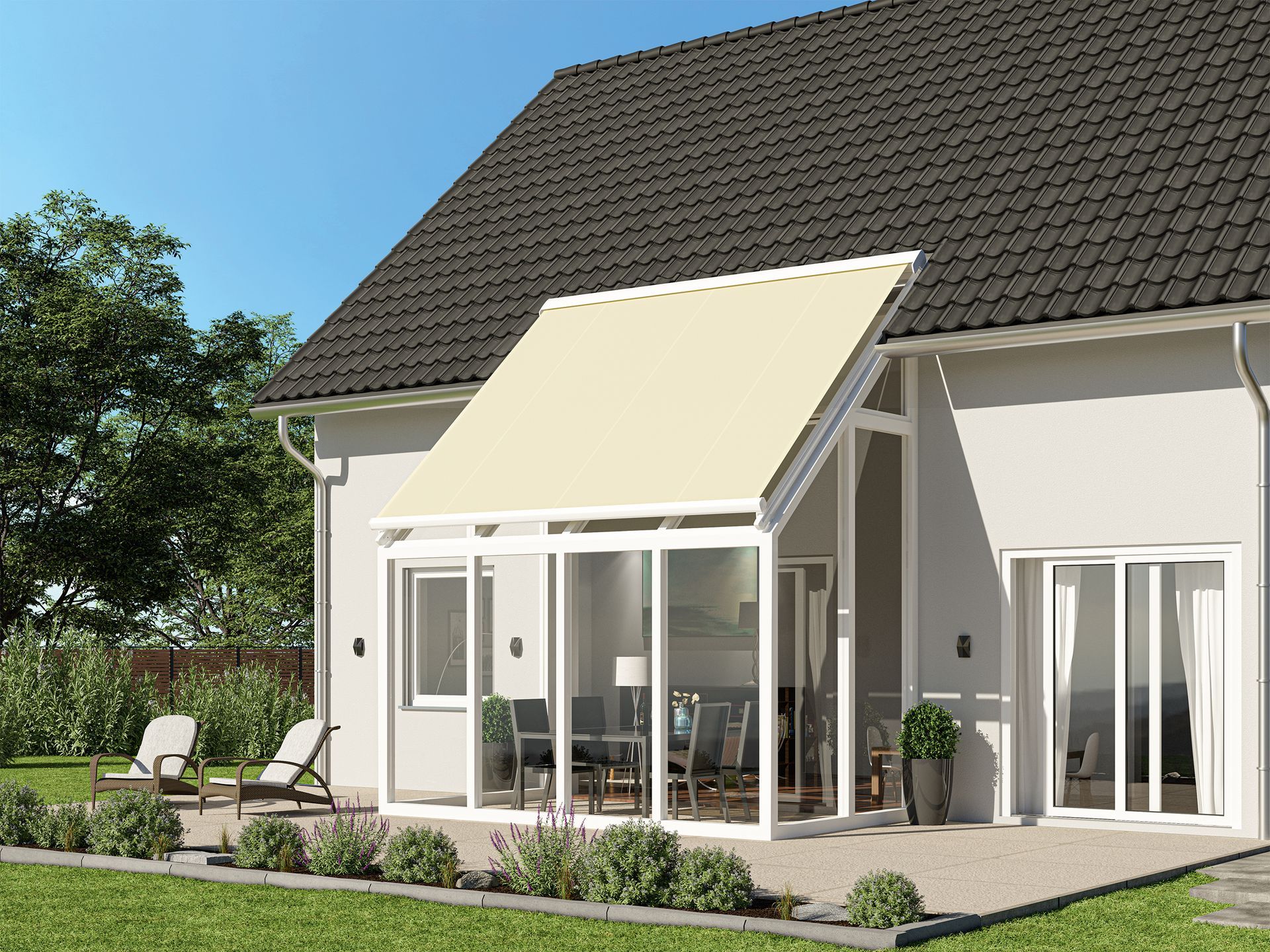 Beigefarbene Markise über einem weißgerahmten Wintergarten, der an ein Haus mit dunklem Dach und gepflegtem Rasen angebaut ist.