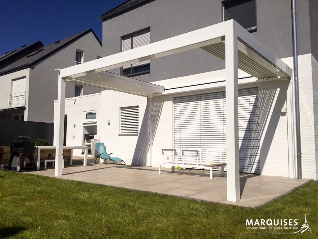 Weiße Pergola an einem modernen weißen Haus über einer Beton-Terrasse mit Rasen.