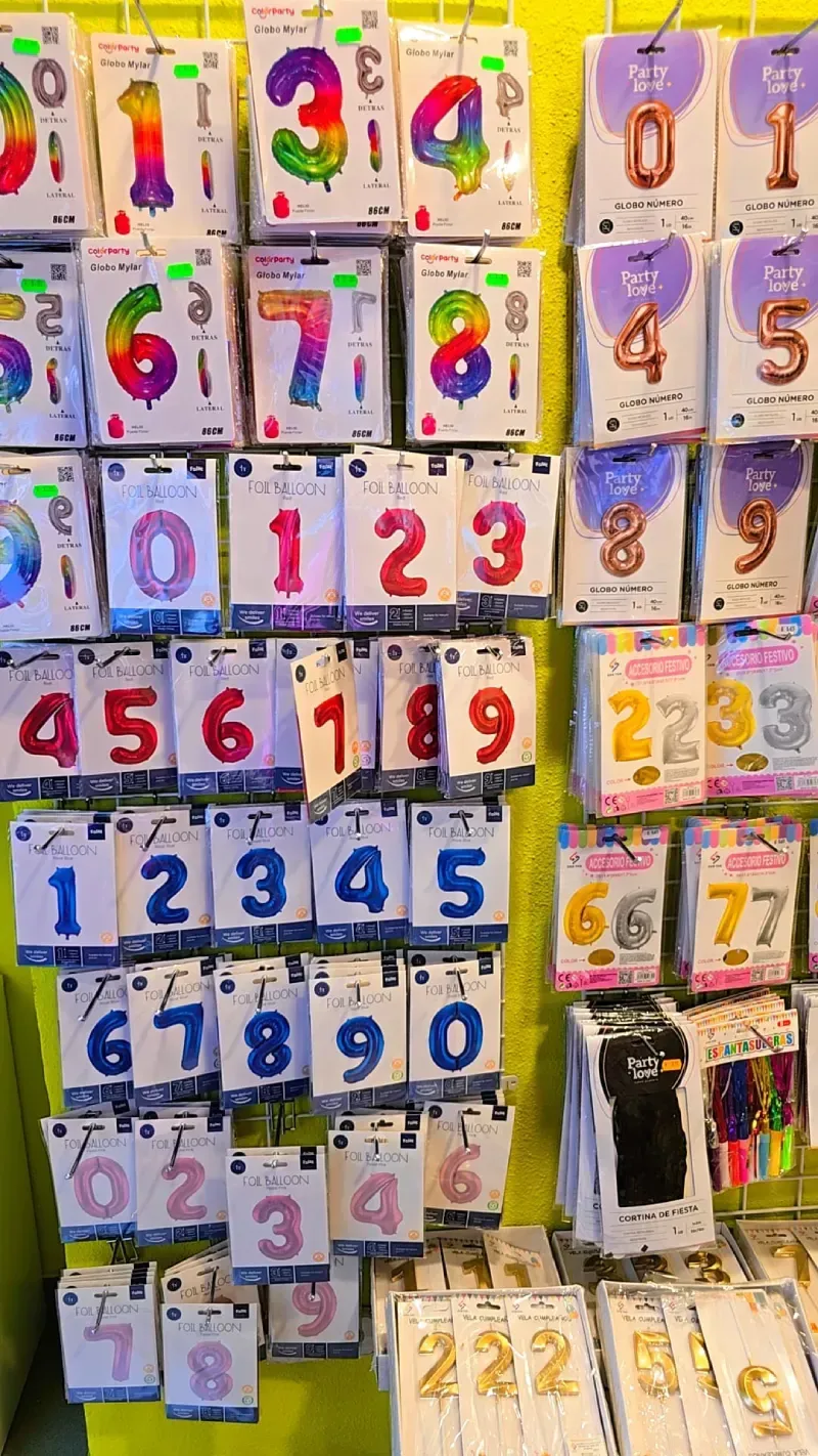 Exhibición de globos de números coloridos en tienda minorista; varios tamaños y colores.