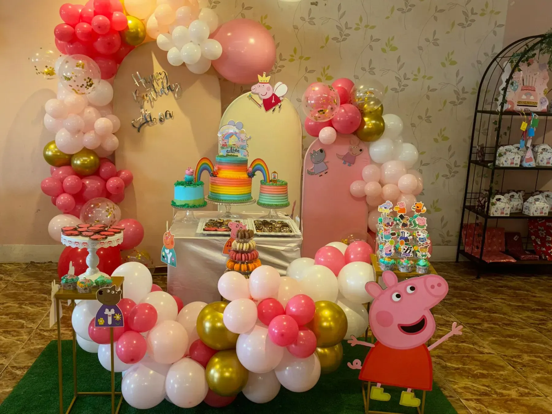 Decoraciones para fiesta de cumpleaños con temática de Peppa Pig: globos, pastel y recorte de personajes de dibujos animados.